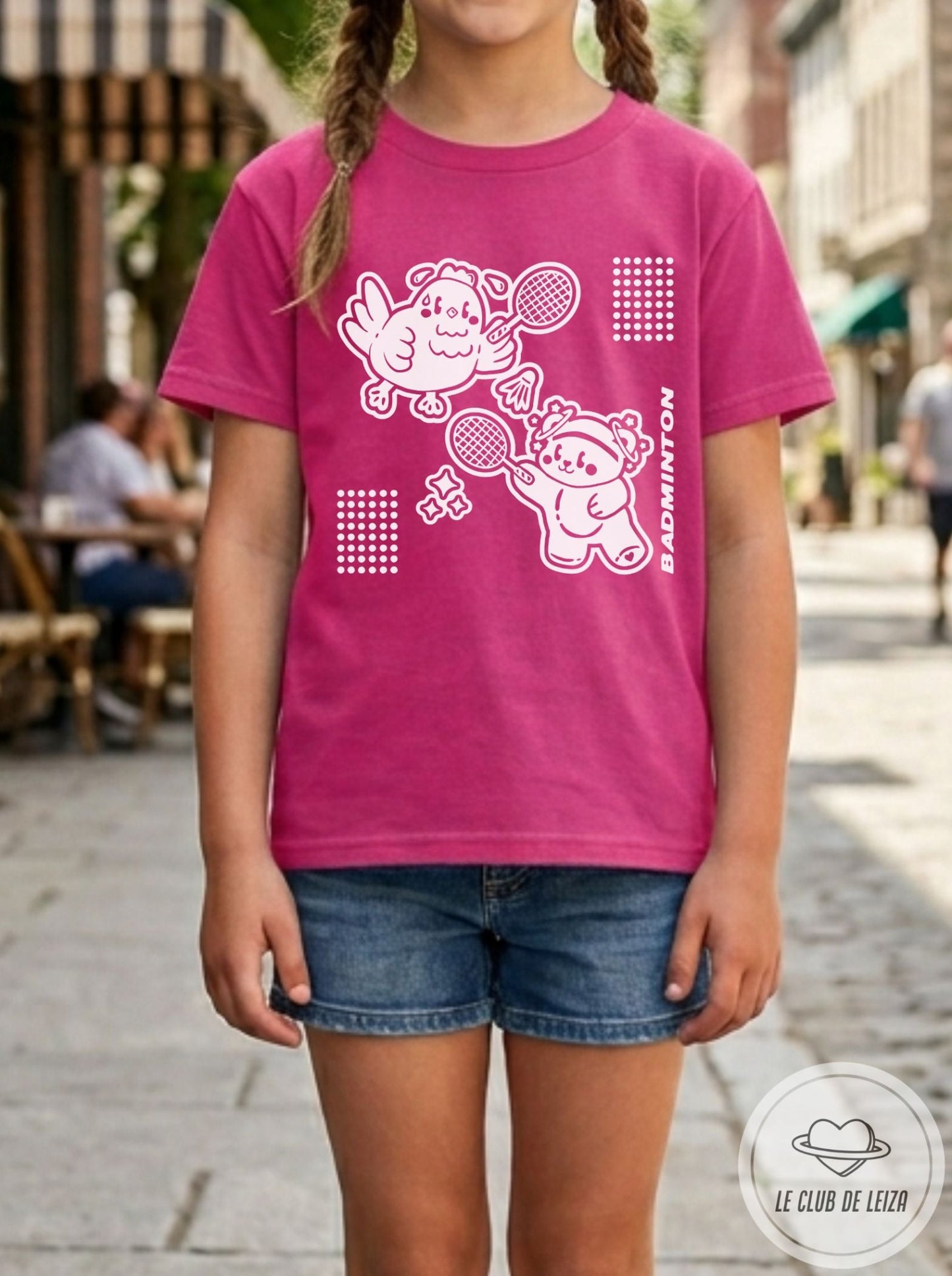Child wearing a pink t-shirt with cartoon characters on a street background